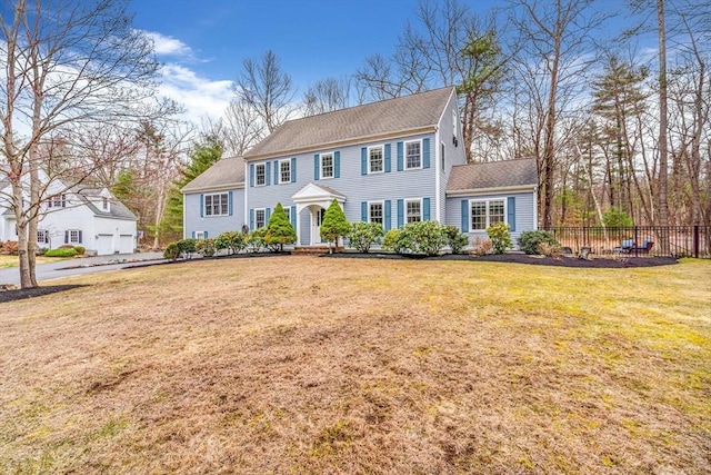view of front of house featuring roof with shingles, a front yard, and fence