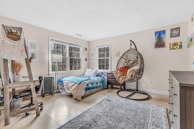 bedroom featuring baseboards, visible vents, wood finished floors, and radiator heating unit