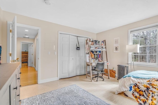 bedroom with baseboards, radiator heating unit, and a closet