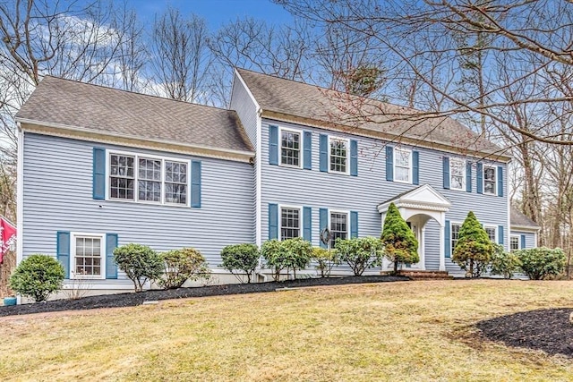 view of front of property with a front lawn and a shingled roof