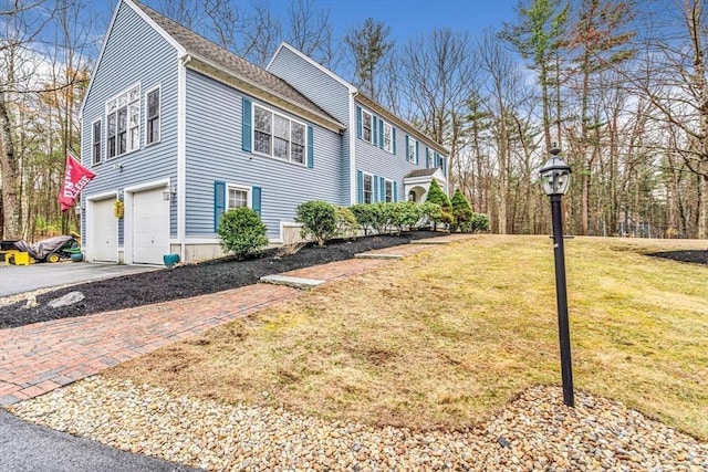 view of home's exterior featuring driveway, an attached garage, a shingled roof, and a yard