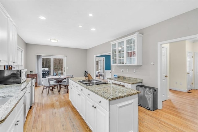 kitchen featuring white cabinetry, black electric cooktop, stainless steel microwave, and a center island
