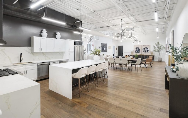 kitchen featuring stainless steel dishwasher, a breakfast bar, sink, white cabinetry, and hanging light fixtures