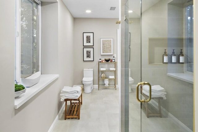 bathroom featuring toilet and a shower with shower door