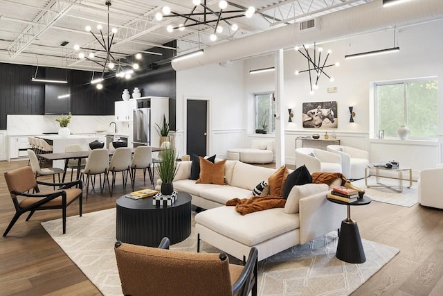 living room with sink, light hardwood / wood-style floors, and a high ceiling