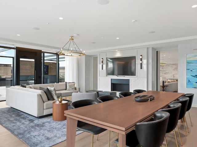 dining space with light wood-type flooring, plenty of natural light, and an inviting chandelier