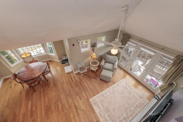 living area featuring light wood-style floors, ceiling fan, baseboards, and vaulted ceiling