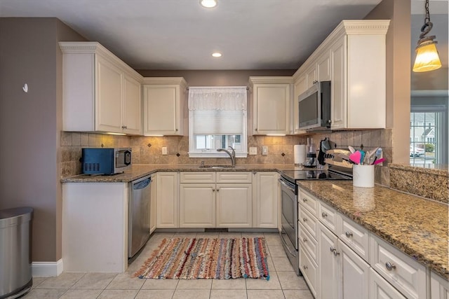 kitchen featuring appliances with stainless steel finishes, plenty of natural light, light tile patterned flooring, and a sink