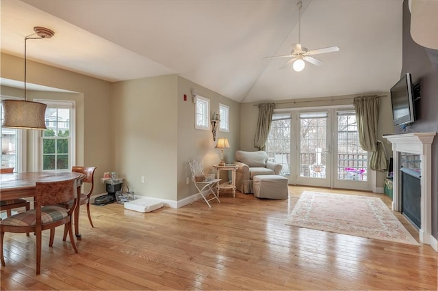 living room featuring light wood-style floors, a fireplace, baseboards, and ceiling fan