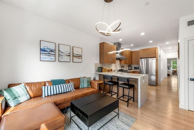 living room with sink, a chandelier, and light hardwood / wood-style flooring