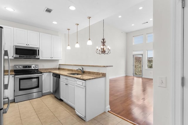 kitchen featuring sink, stainless steel appliances, white cabinets, dark stone counters, and light tile patterned flooring