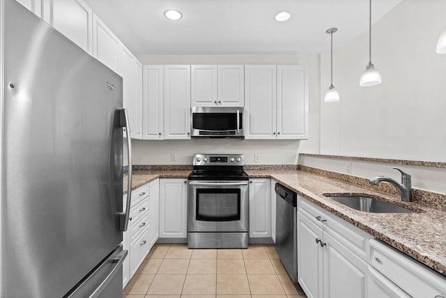 kitchen featuring appliances with stainless steel finishes, sink, light tile patterned floors, white cabinets, and hanging light fixtures