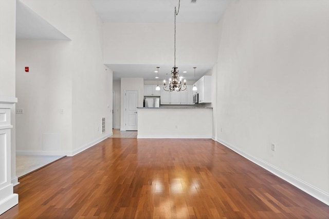 unfurnished living room with a notable chandelier and wood-type flooring