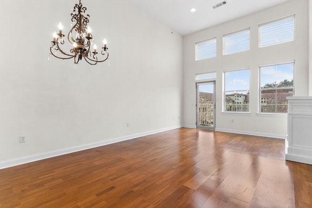 spare room featuring hardwood / wood-style flooring, a high ceiling, and a chandelier