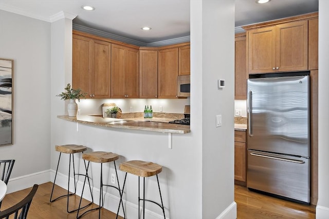 4 Lincoln Pl Unit 4, Boston, MA 02129 - kitchen featuring appliances with stainless steel finishes, a breakfast bar area, baseboards, light wood-style flooring, and recessed lighting