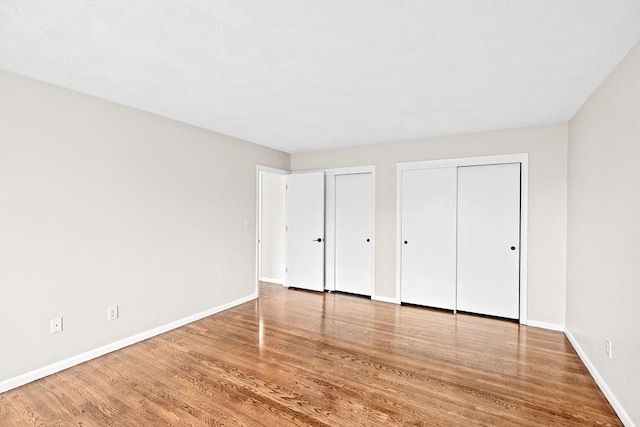 41 Centre Unit 208, Brookline, MA 02446 - unfurnished bedroom featuring two closets, baseboards, and wood finished floors