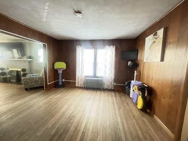 98-100 Fenwick St, Springfield, MA 01109 - living area with radiator heating unit, wood finished floors, a brick fireplace, plenty of natural light, and wood walls