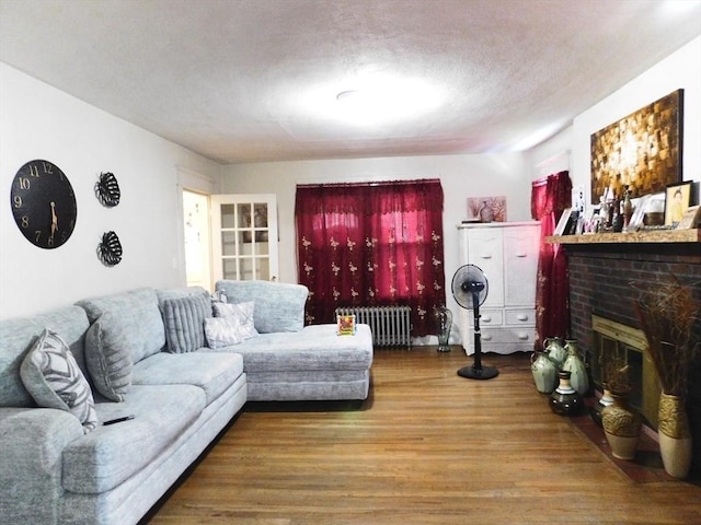 98-100 Fenwick St, Springfield, MA 01109 - living room with radiator heating unit, wood finished floors, a fireplace, and a textured ceiling