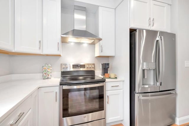 kitchen with stainless steel appliances, white cabinets, light countertops, and wall chimney range hood