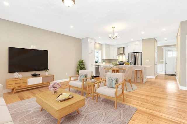 living room with recessed lighting, light wood-style flooring, an inviting chandelier, and baseboards