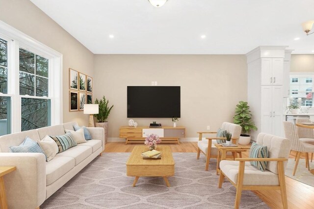 living room with plenty of natural light, recessed lighting, light wood-type flooring, and baseboards