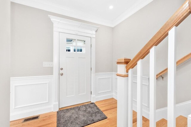 entrance foyer featuring visible vents, light wood finished floors, crown molding, and stairway