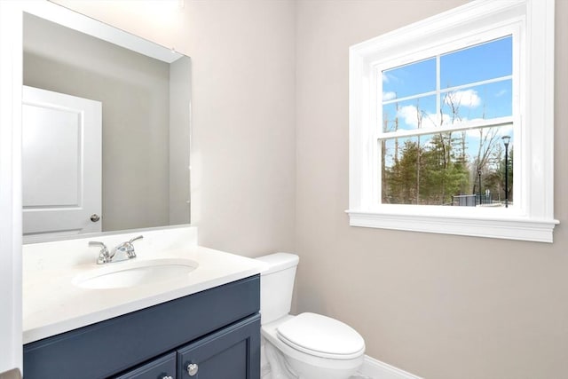 bathroom with toilet, vanity, and baseboards