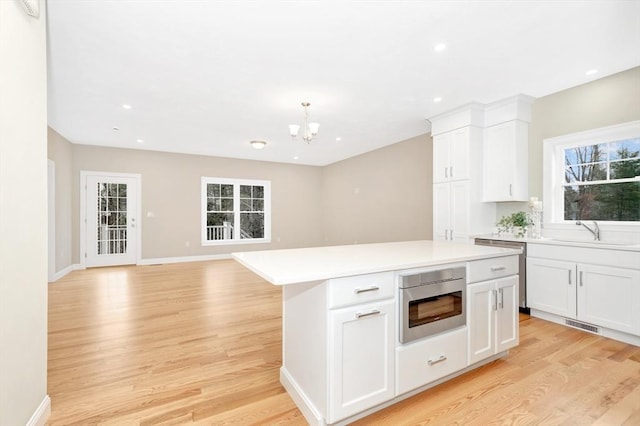 kitchen featuring built in microwave, plenty of natural light, light wood-style flooring, and a sink