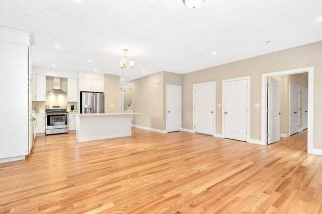 unfurnished living room featuring baseboards, light wood-type flooring, and a chandelier