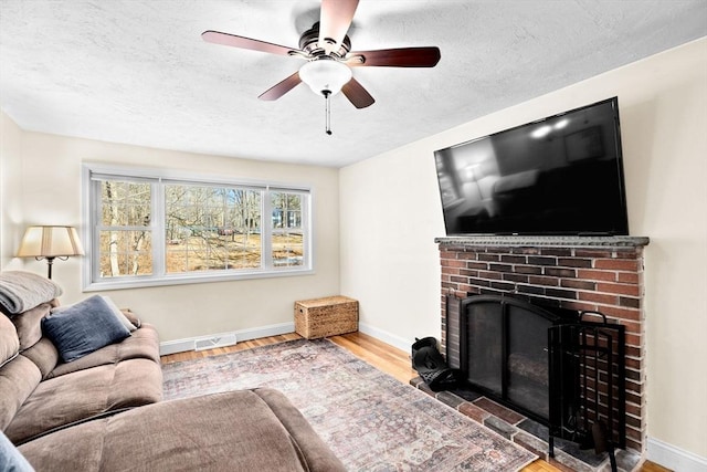 living room featuring ceiling fan, hardwood / wood-style floors, and a fireplace