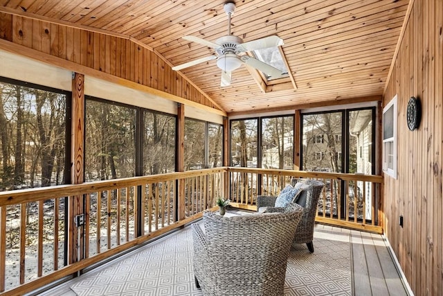 unfurnished sunroom featuring ceiling fan, vaulted ceiling with skylight, and wood ceiling