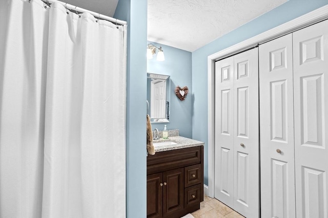 bathroom featuring a textured ceiling, tile patterned floors, vanity, and walk in shower