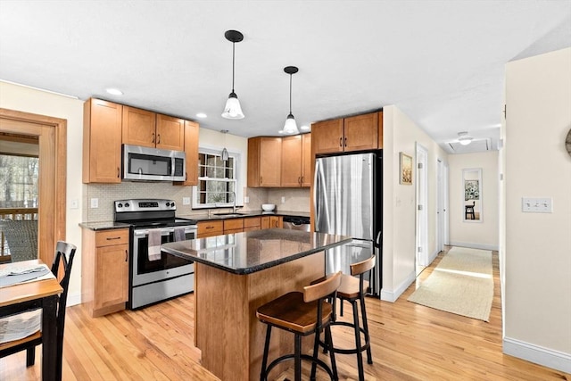 kitchen featuring hanging light fixtures, sink, backsplash, a center island, and stainless steel appliances