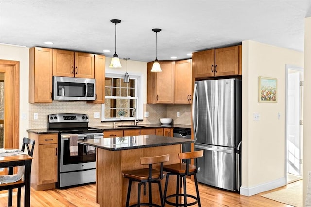 kitchen featuring pendant lighting, sink, a kitchen island, light hardwood / wood-style floors, and stainless steel appliances