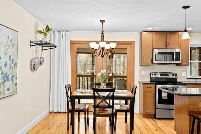 kitchen with hanging light fixtures, light hardwood / wood-style flooring, stainless steel appliances, and tasteful backsplash