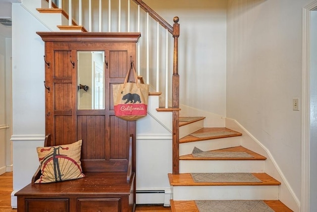 staircase with hardwood / wood-style floors and baseboard heating