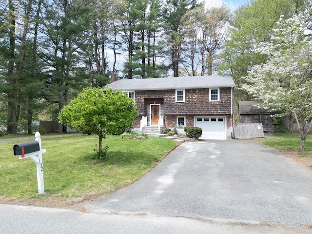 bi-level home with asphalt driveway, an attached garage, and a chimney