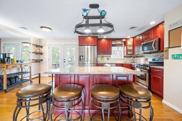 kitchen featuring appliances with stainless steel finishes, dark brown cabinets, a kitchen island, tasteful backsplash, and a sink