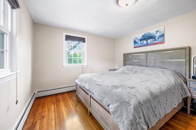 bedroom with baseboard heating and wood finished floors