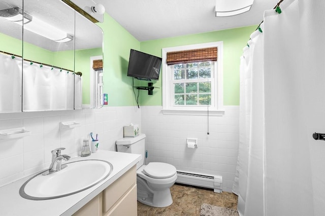 bathroom with a baseboard heating unit, tile walls, toilet, a wainscoted wall, and vanity