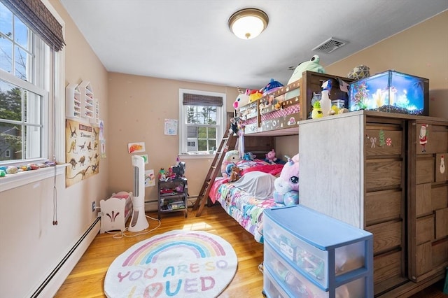 bedroom featuring a baseboard heating unit and wood finished floors