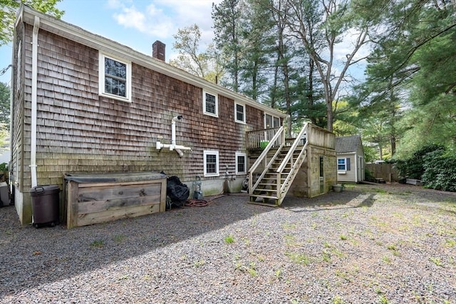 rear view of property featuring stairs, a chimney, an outdoor structure, a storage unit, and a deck