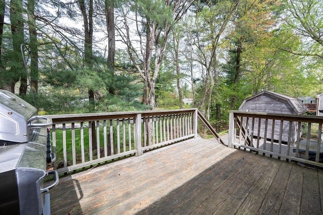 wooden terrace with a shed, an outdoor structure, and view of scattered trees