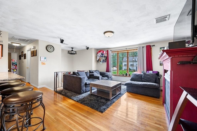 living area with light wood finished floors, baseboards, and a textured ceiling