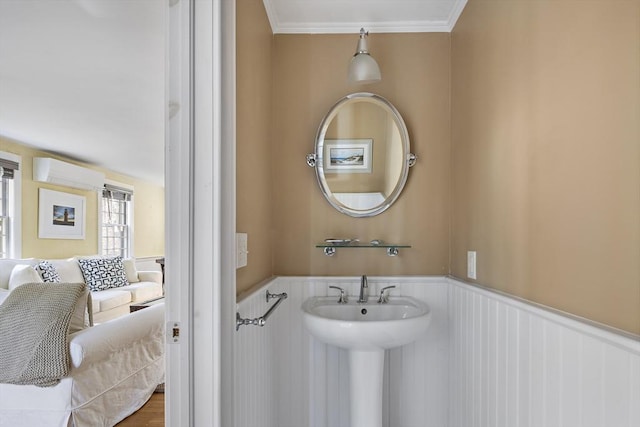 8 School House Vlg, Oak Bluffs, MA 02557 - bathroom with wainscoting, crown molding, a wall mounted air conditioner, and a sink