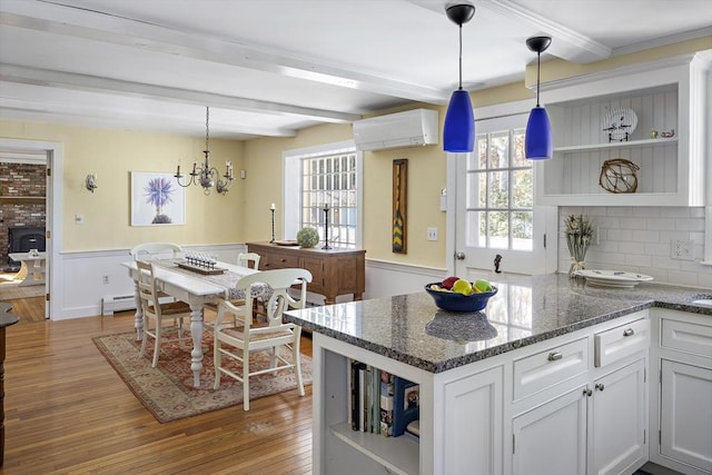 8 School House Vlg, Oak Bluffs, MA 02557 - kitchen with open shelves, beamed ceiling, a wall mounted air conditioner, wood finished floors, and a wainscoted wall
