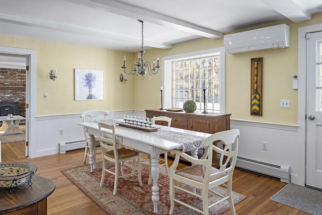 8 School House Vlg, Oak Bluffs, MA 02557 - dining room with beamed ceiling, baseboard heating, wood finished floors, wainscoting, and a chandelier