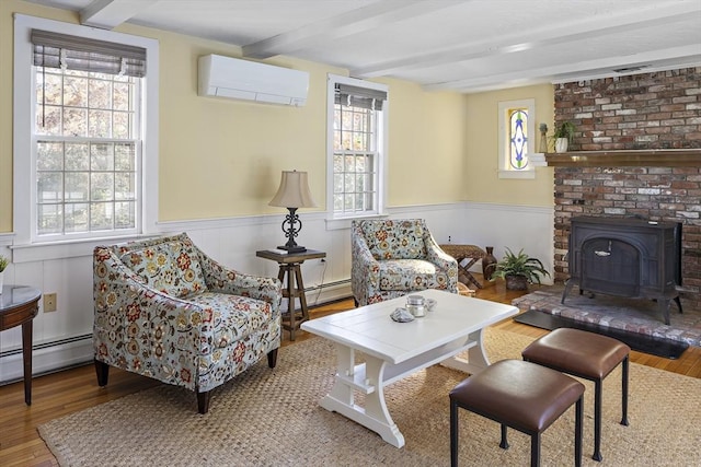 8 School House Vlg, Oak Bluffs, MA 02557 - living room with an AC wall unit, wainscoting, beam ceiling, wood finished floors, and a wood stove