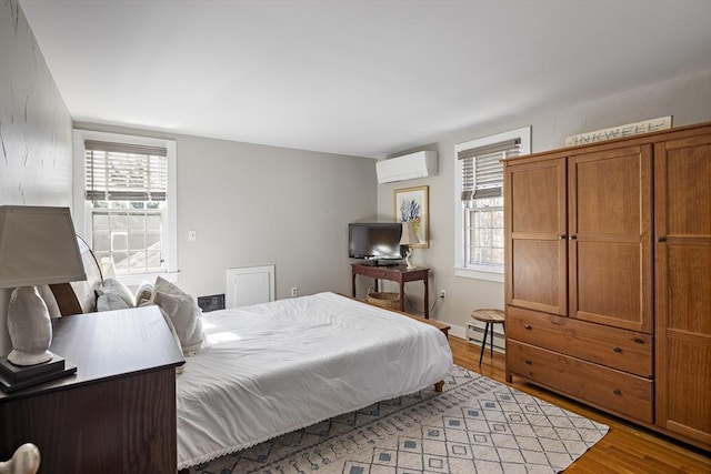 8 School House Vlg, Oak Bluffs, MA 02557 - bedroom featuring a wall mounted air conditioner, wood finished floors, and baseboard heating