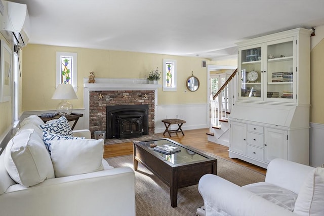 8 School House Vlg, Oak Bluffs, MA 02557 - living room with plenty of natural light, wood finished floors, stairway, a wainscoted wall, and a wall mounted air conditioner